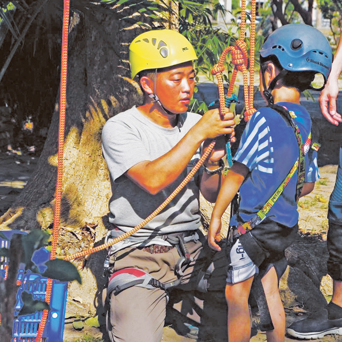 陳胤丰正在協助兒童裝置好攀樹器具。（陳胤丰提供）