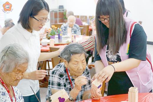 樂齡小志工從旁協助長輩進行風獅爺彩繪。(許峻魁攝)