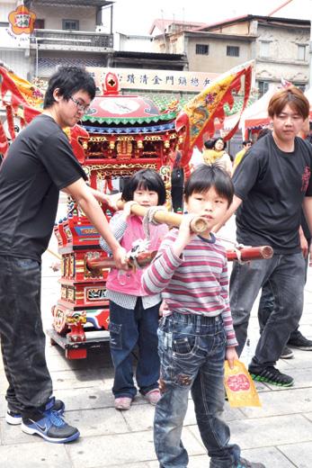 　「民俗技藝及藝陣體驗博覽會」在金城鎮總兵署前廣場熱鬧舉辦：現場許多父母親帶著孩子參與扛神輦、坐蜈蚣座的體驗活動。（莊煥寧攝）