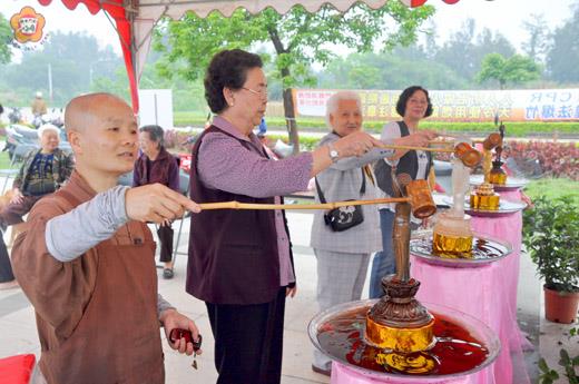 浴佛節，靜慮精舍昨日假向陽吉第活動中心廣場辦理「齋戒護生祈福」活動，德契法師帶領信眾虔誠的浴佛。（許加泰攝）