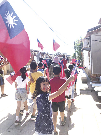 國慶日前夕,垵湖師生攜國旗遊后湖村落,讓小朋友認識代表國家的國旗,知道國慶日的意義,滋養愛國意識。(垵湖分校提供)