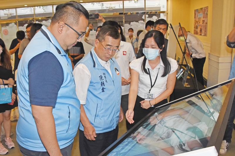 秘書長陳朝金與觀光處長丁健剛聽取廠商說明各項旅遊服務系統特色。(莊煥寧攝)