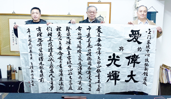 書法大師張炳煌（中）贈與金門家扶中心墨寶「愛的偉大與光輝」，揭櫫家扶的理念與精神。（家扶中心提供）