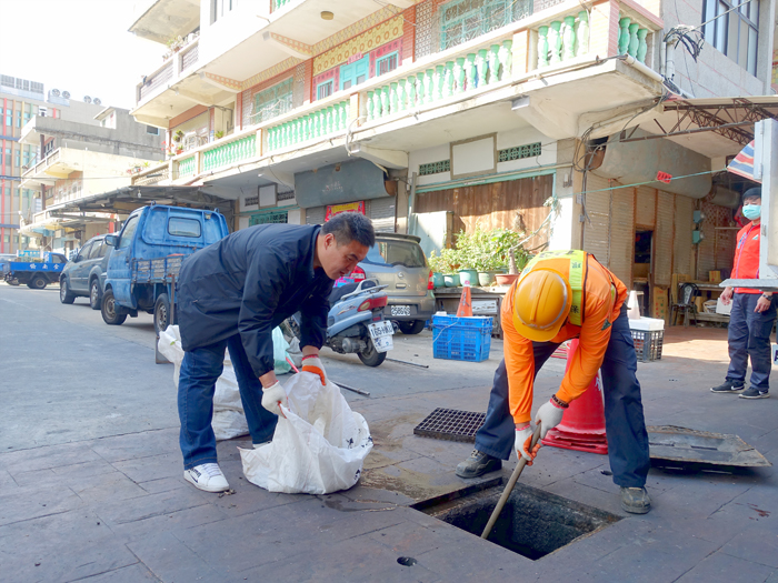 金城鎮長李誠智亦參與東門市場的環境整理，協助挖除水溝蓋下的雜物。（金城鎮公所提供）