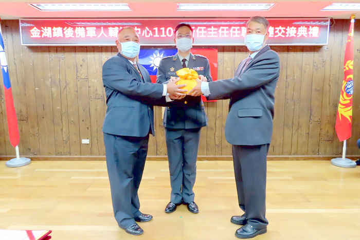 金湖鎮後備軍人輔導中心舉辦交接典禮，在金門縣後備中心主任許澤鑫（中）上校監交下，由陳家興（左）交接印信予李遷居（右），與會貴賓紛紛獻上祝賀，最後全體人員也合影留念。  （陳麗妤攝）