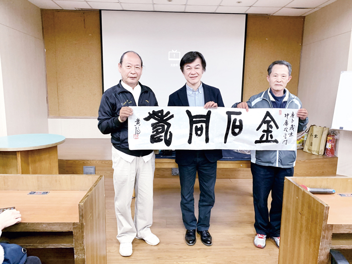 金門縣書法學會邀請華梵大學黃智陽院長（中）來金開講，現場揮毫的墨寶贈與對書法展現濃厚興趣的幸運民眾。（書法學會提供）