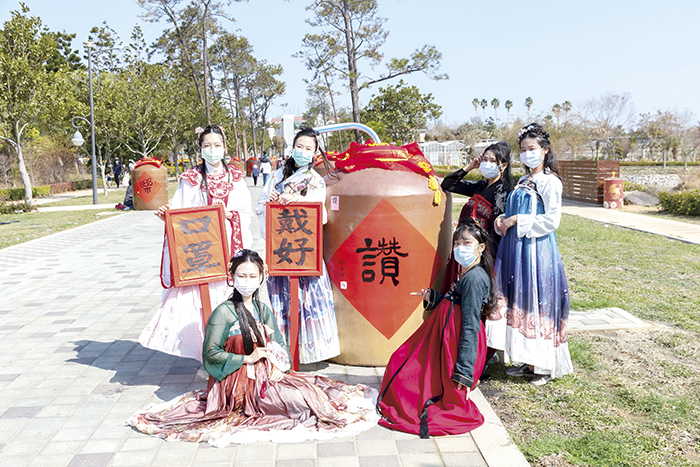 在「防疫優先」的大前提下，金門縣政府順勢將今年春節定位為「防疫平安年」，雖然大幅減少春節群聚活動，但也全力營造年節氛圍，圖為林務所與金酒公司及書法協會合作，邀請書法大師在報廢酒甕上書寫吉祥話與春聯，營造「酒香藝文大道」特色景點，希望與鄉親攜手共度「牛轉乾坤」的新年。（縣府提供）