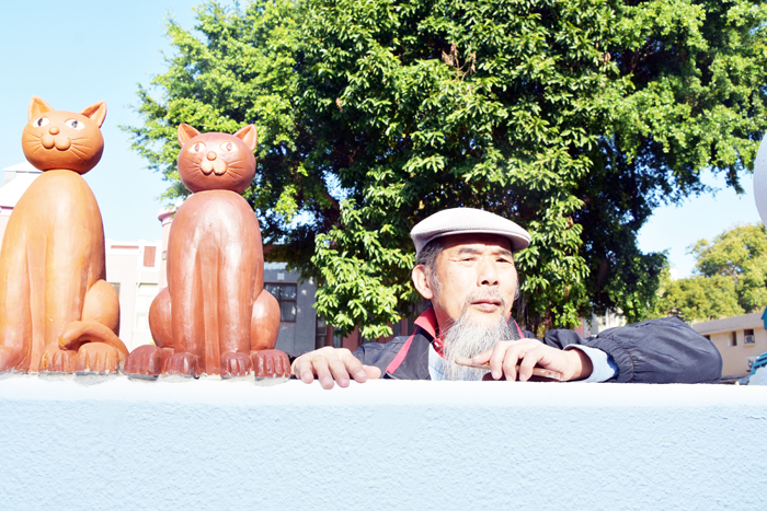 縣籍藝術家吳鼎信以巧手童心塑造貓塑像，塑立在牆頭的貓咪群像成為路旁的可愛風景。（詹宗翰攝）