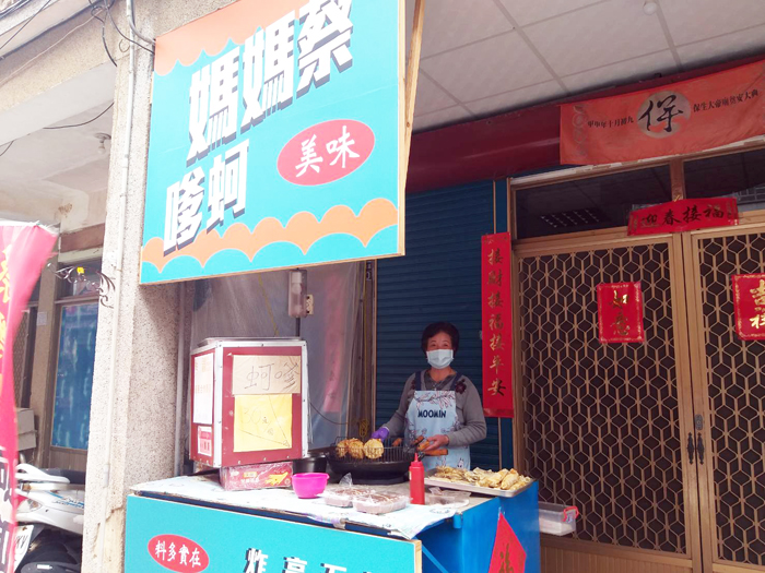 西方老街軍事標語與裝飾相映襯,充滿戰地意象情境,被稱為「軍事一條街」,吸引許多遊客拍照打卡。圖為「蔡媽媽蚵嗲」的地方小吃。(許加泰攝)