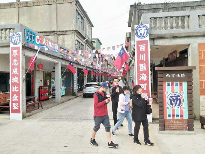 西方老街軍事標語與裝飾相映襯，充滿戰地意象情境，被稱為「軍事一條街」，吸引許多遊客拍照打卡。圖為集樂市街的意象入口處，引人注目。（許加泰攝）