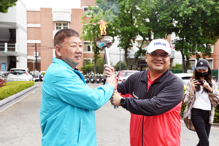 110年全中運聖火由雲林縣傳遞到金門縣，由鎮西國小校長陳嘉銘（右）率隊將聖火交給金門縣。（詹宗翰攝）