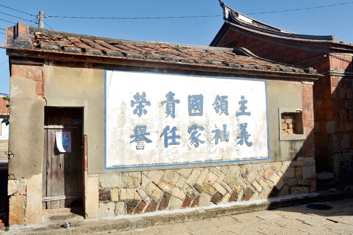藩伯宗祠前民宅牆上的精神標語,昭示著聚落過去軍民共處的年代。(詹宗翰攝)