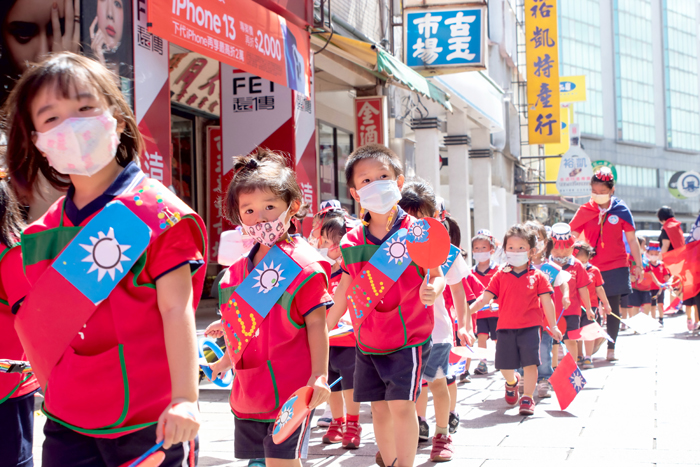 幼生在金城市區進行慶祝國慶日的遊街，孩子們穿戴著自己手作的小國旗、國旗帽、國徽肩帶，沿途中大聲嚷著「中華民國生日快樂」！（寶貝園地幼兒園提供）