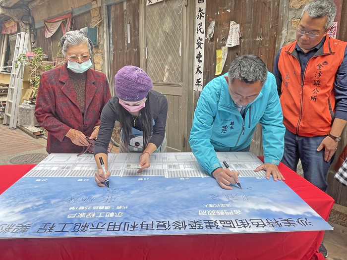 縣長楊鎮浯代表金門縣政府與信義街6間示範工程住戶代表,一同簽下契約書。(陳麗妤攝)