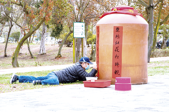 林務所迎新春假日花市，邀請書法老師在大酒甕上揮毫創意賀詞。（林務所提供）