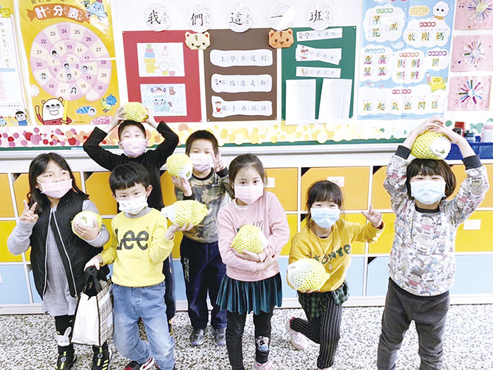 金門縣各國中小學生接受到台肥公司贈送鳳梨釋迦，開心的拿起來在鏡頭前拍照合影。（教育處提供）