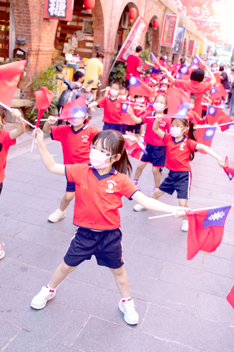 金城寶貝園地幼兒園舉辦國慶遊街教學活動，小朋友身穿國旗裝、揮舞著國旗，沿街祝賀「中華民國生日快樂」。（寶貝園地幼兒園提供）