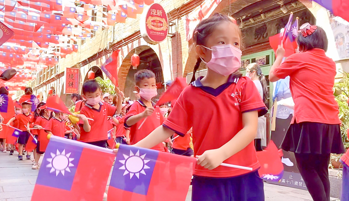 金城寶貝園地幼兒園舉辦國慶遊街教學活動，小朋友身穿國旗裝、揮舞著國旗，沿街祝賀「中華民國生日快樂」。（寶貝園地幼兒園提供）