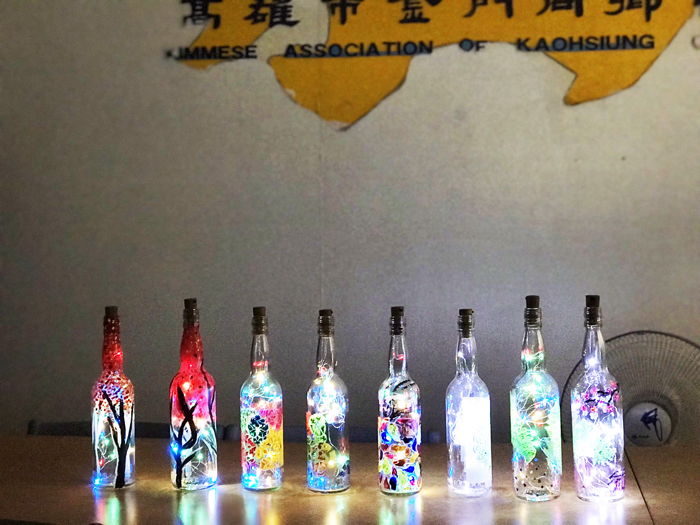 高雄市金江社區照顧關懷據點日前又推出彩繪酒瓶活動，邀金門女兒蔡美慧到據點傳授玻璃彩繪技巧，10餘位志工學員也開心的投入學習並展現成果。（高雄市金江社照據點提供）