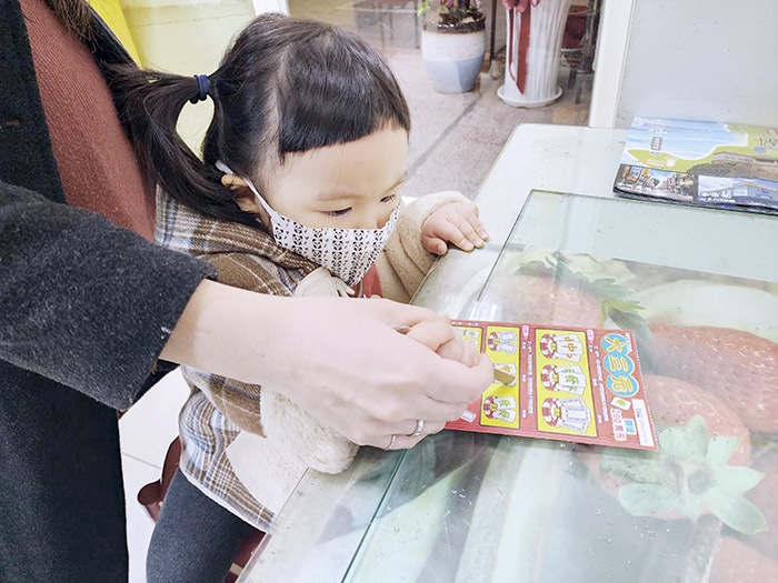 有民眾就由小朋友挑選刮刮樂,並借助小朋友的手希望中大獎。(許峻魁攝)