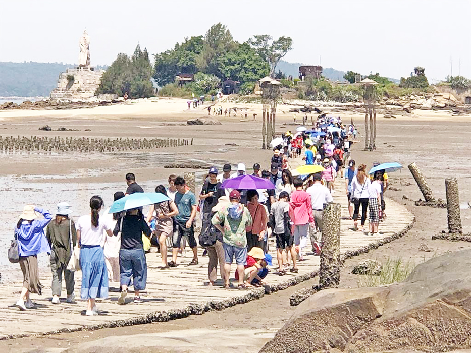 建功嶼是金門版「摩西分海」特色景點,吸引遊客絡繹來訪。(李金生攝)