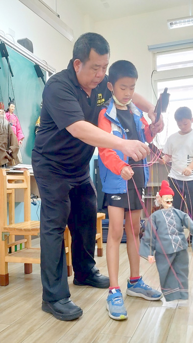 蔡遠進老師（左一)教導學童操偶、調整身體姿勢。（中正國小提供）