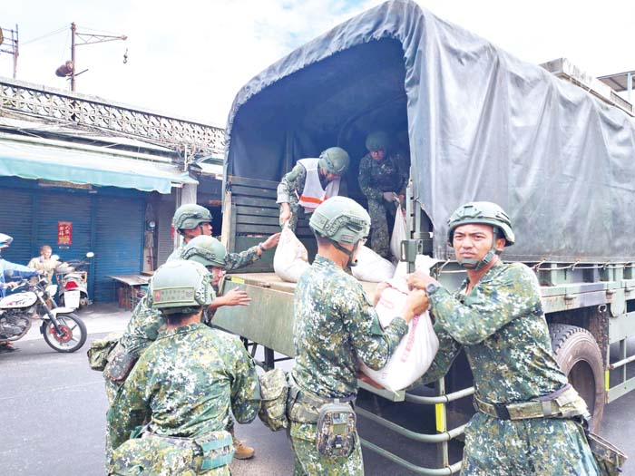 軍方以接力方式,將一袋袋沙包放置到代天府前。(許峻魁攝)