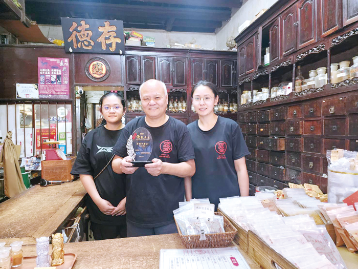 存德中藥房第5代的顏及人(中)與一對女兒合影。(許峻魁攝)