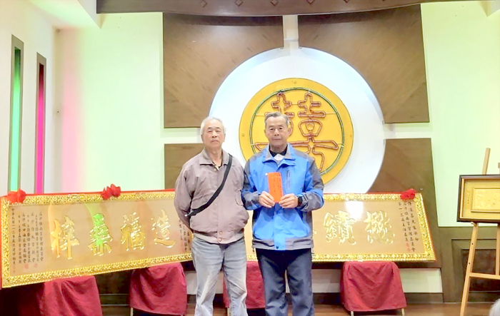 臺北市金門同鄉會理事長許奮鬥特以媽媽許張寶羨的名義,委託許明義老師(左)捐贈給宗親會貳萬元,並由理事長許榮緒(右)受領。(后沙許氏宗親會提供)