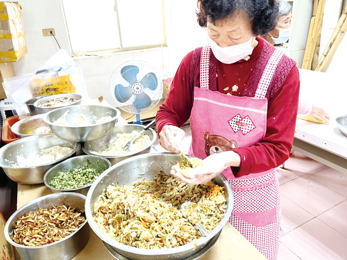 婆婆媽媽雙手馬不停蹄將餡料包住菜粿中。（高凡淳攝）