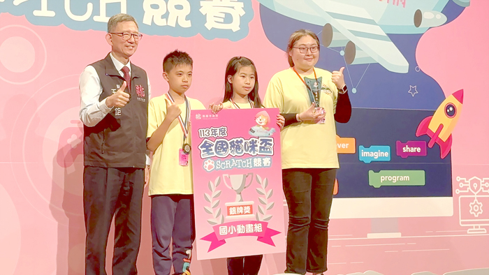金鼎國小學生蔡亦閔(左二)、林庭安(右二)在全國貓咪盃Scratch競賽榮獲國小動畫組銀牌獎,由老師姜惠蓉(右一)陪同上台接受桃園市副市長王明鉅(左一)頒獎表揚。(教育處提供)