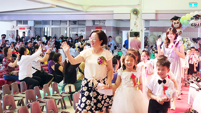 金城幼兒園溫馨舉行113級畢業典禮,師長帶著畢業生進場,家長為幼兒拍攝紀念畫面。(城幼提供)