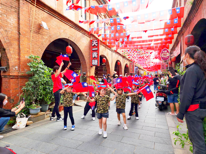 寶貝園地昨日前往金城街頭遊行,手拿國旗頭戴國旗帽,一起慶祝國慶日。(許峻魁攝)
