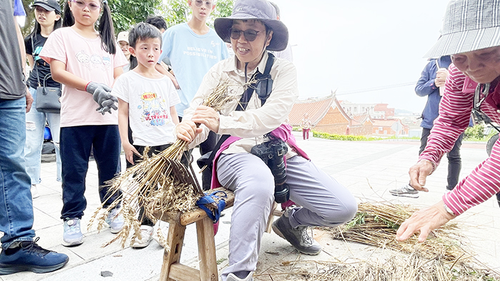 親子在志工帶領下,操作麥梳及「連耞」等農事工具。(陳麗妤攝)