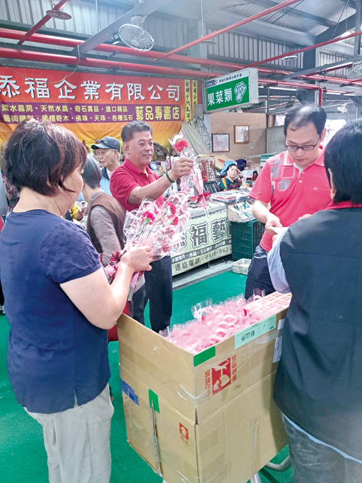 金湖鎮長陳文顧走訪菜市場,向婆婆媽媽們獻上康乃馨。(金湖鎮公所提供)