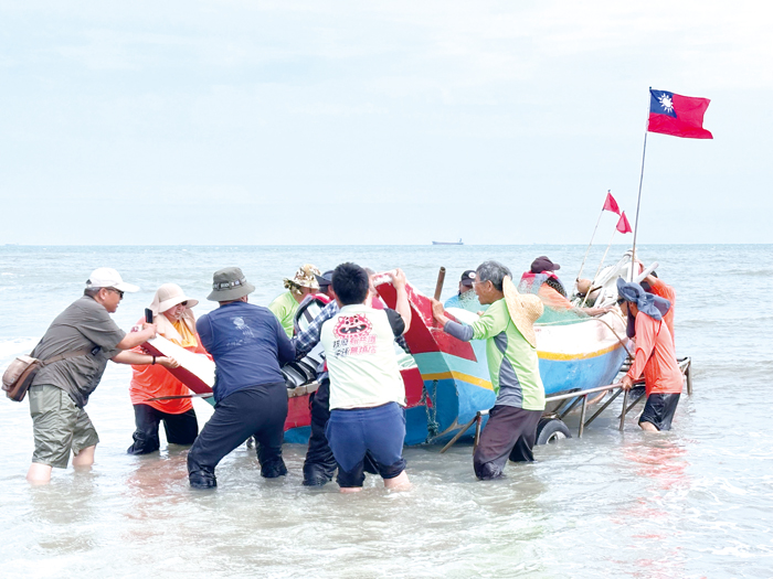 將船隻從運送船架上分離並推入海中。(張郁姍攝)