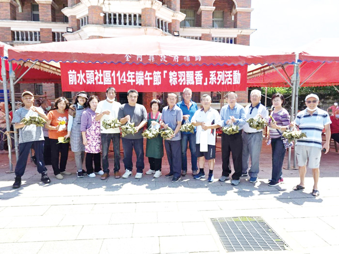 水頭社區舉辦包粽活動,志工們與貴賓開心捧著美味粽子合影。(許峻魁攝)