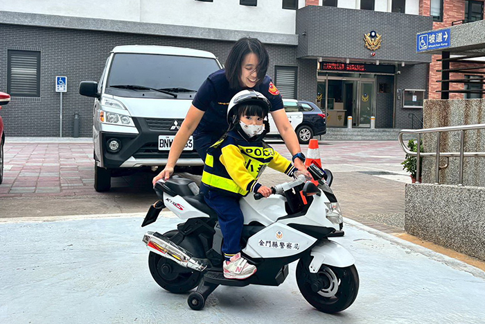 私立羅伊頓幼兒園幼幼班與小班孩童前往金城分局金寧分駐所參訪，在員警與老師的協助下孩子們身穿整齊警察服裝、騎著小警用機車。（金城分局提供）