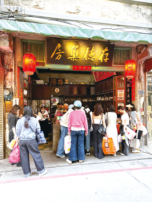 許多遊客在金城老街上的百年老字號「存德藥房」門口，購買招牌胡椒粉、五香粉等香料。（陳冠霖攝）