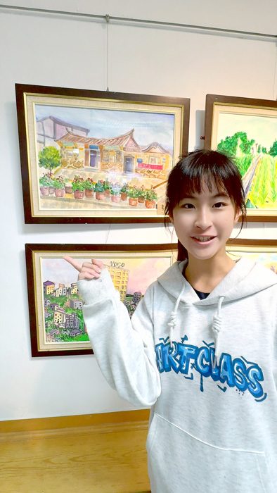 李欣桐開心的跟作品合影。
（讀者提供）