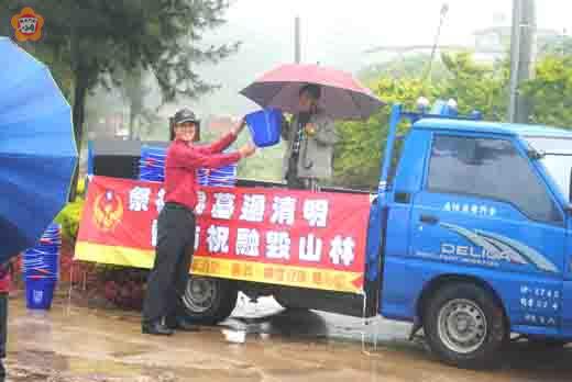   金寧消防分隊結合婦宣隊冒雨在中東堡路口贈送小水桶宣導，讓掃墓祭祖的鄉親隨手滅火。（金寧消防分隊提供）