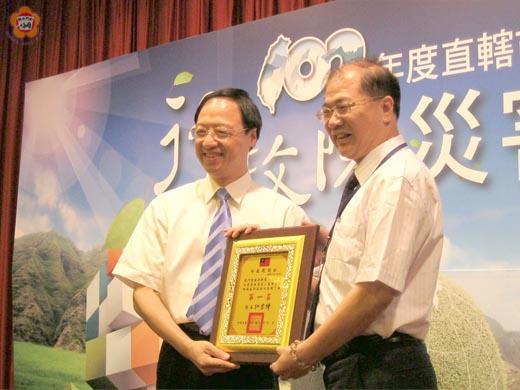   金門縣消防局「102年災害防救演習」，連續四度蟬聯全國丁組第一名：行政院長江宜樺頒發102年全國災害防救演習績優獎牌給李沃士縣長。（照片由金門縣政府台北服務處主任陳永富提供）