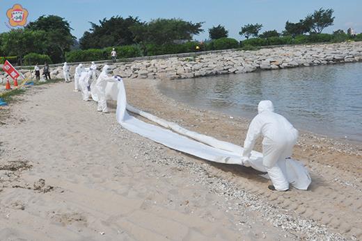 　金門縣102年海洋油污染及毒災應變演練昨在雄獅堡外海及沙灘舉行，過程中除了海上攔油索的布放與抽油作業操演，岸際也有除污的應變及清理。（莊煥寧攝）