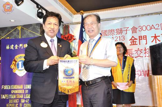   金門獅子會、木蘭獅子會、金龍獅子會聯合授證暨會長、會職員交接活動昨舉行：獅子會300A2區總監李朝永致贈紀念章、旗給到場致賀觀禮的李沃士縣長。（莊煥寧攝）