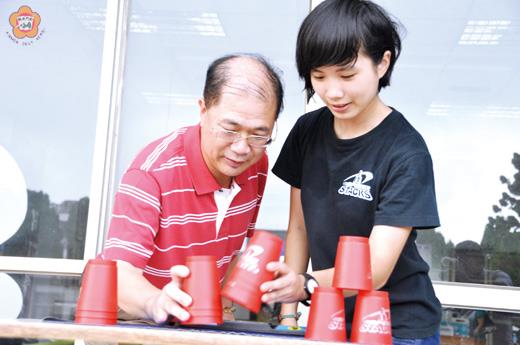   金門縣長李沃士（左）與「世界疊杯冠軍」林孟欣（右）分享疊杯的技巧與樂趣。（翁碧蓮攝）