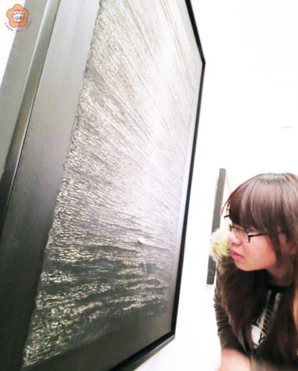   水波橫颭灩，光束縱煥綺；凸起一點白，畫上有「寄意」！一位參觀者正靠近〈寄意〉上的白點，仔細端詳。（張建騰攝）