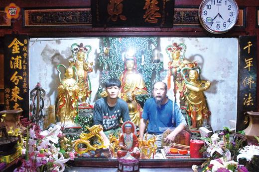 　金門本土藝家吳鼎信與吳子魁父子聯手完成後浦靈濟古寺(觀音亭) 觀音佛祖神像修復工作，並於佛像前合照。 （吳鼎信提供）