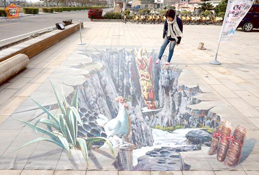   金門建縣一百年3D立體畫展，五幅立體畫於五鄉鎮展出，民眾透過與畫互動產生趣味聯結，圖為「開創時期」畫作，被民眾形容烈嶼文化館前破了一個大洞！（陳麗妤攝）