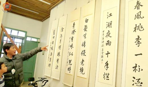 陳國琍邀村童一起觀賞王金鍊的書法作品。（張建騰攝）