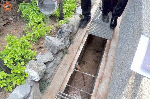 昇恆昌人員帶媒體到現場實測，將水倒入花圃，立刻從排水管流進一旁水溝，水溝則通往汙水下水道，證明該排水管並非議員所指之「偷排廢水暗管」。（陳冠霖攝）